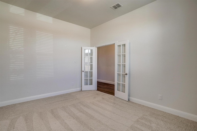 spare room featuring light carpet and french doors