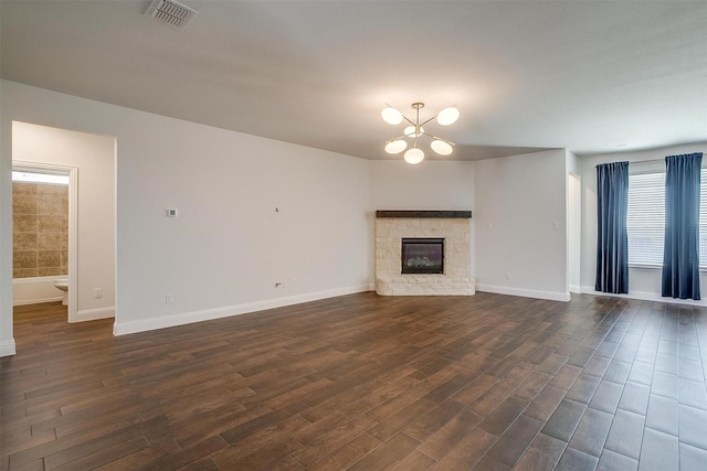 unfurnished living room with dark hardwood / wood-style floors, a notable chandelier, and a fireplace