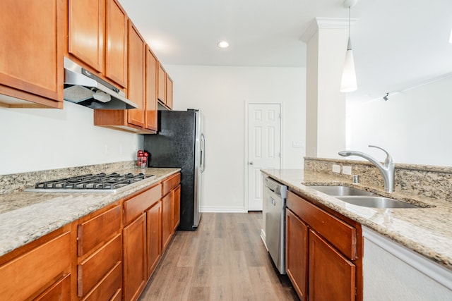 kitchen featuring sink, decorative light fixtures, light wood-type flooring, appliances with stainless steel finishes, and light stone countertops