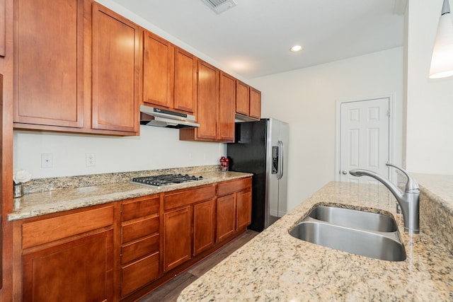 kitchen with light stone counters, sink, and appliances with stainless steel finishes