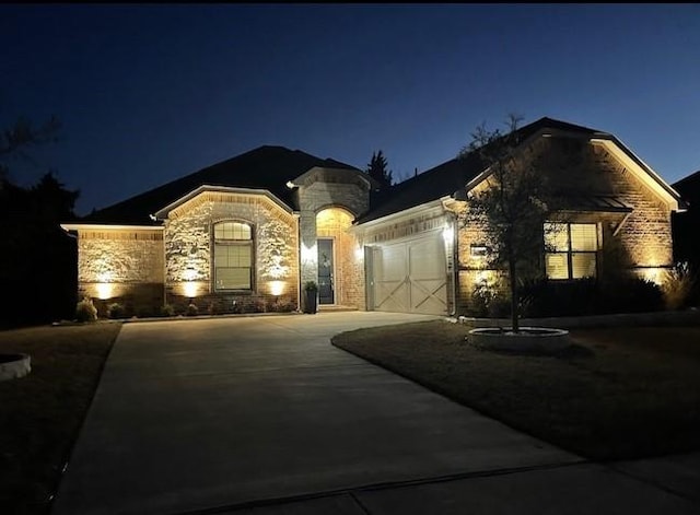 french country style house featuring stone siding, concrete driveway, and an attached garage