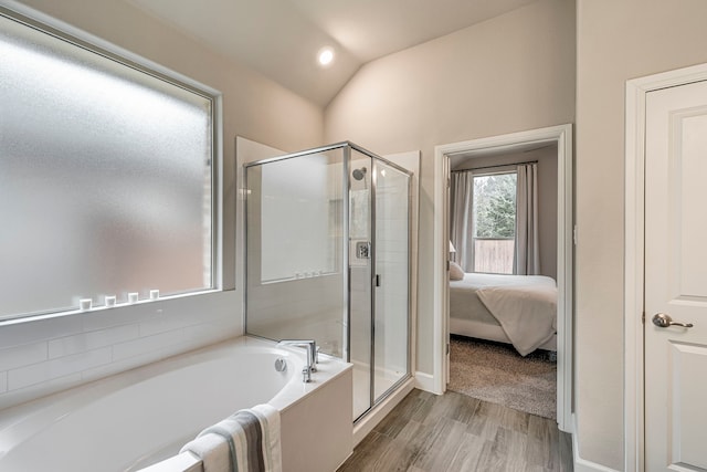 ensuite bathroom featuring wood finished floors, a shower stall, vaulted ceiling, ensuite bathroom, and a garden tub