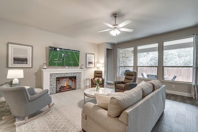 living room with ceiling fan, a tile fireplace, baseboards, and wood finished floors