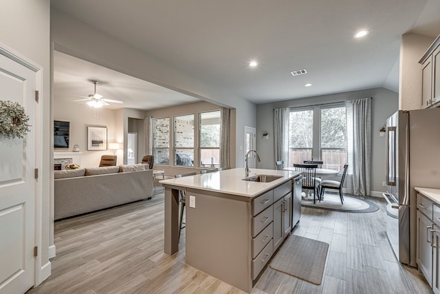 kitchen featuring visible vents, gray cabinetry, a sink, stainless steel appliances, and a fireplace