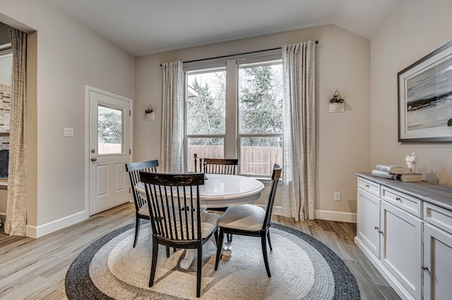 dining room with vaulted ceiling, baseboards, and light wood finished floors