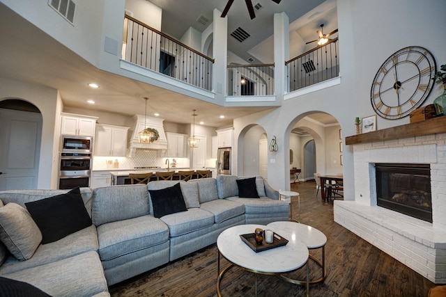 living room with dark hardwood / wood-style flooring, a brick fireplace, and ceiling fan