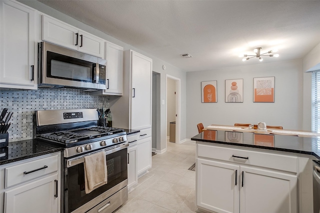 kitchen featuring white cabinetry, appliances with stainless steel finishes, light tile patterned flooring, and decorative backsplash