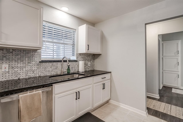 kitchen featuring sink, dishwasher, white cabinetry, dark stone countertops, and decorative backsplash