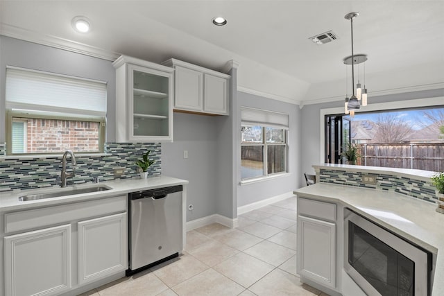 kitchen featuring visible vents, decorative backsplash, appliances with stainless steel finishes, light countertops, and a sink