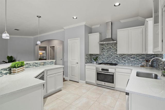 kitchen featuring arched walkways, light tile patterned floors, stainless steel appliances, a sink, and wall chimney exhaust hood