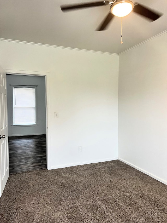 spare room featuring dark colored carpet, ornamental molding, and ceiling fan