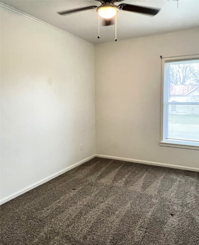 spare room with ceiling fan and dark colored carpet