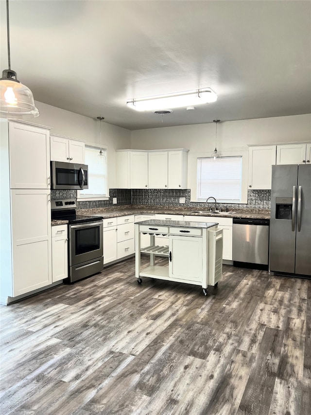 kitchen with white cabinetry, sink, decorative light fixtures, and stainless steel appliances