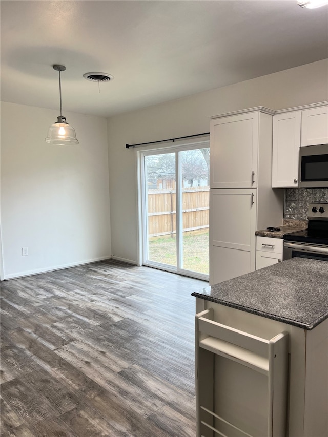 kitchen featuring wood-type flooring, dark stone counters, white cabinets, and appliances with stainless steel finishes