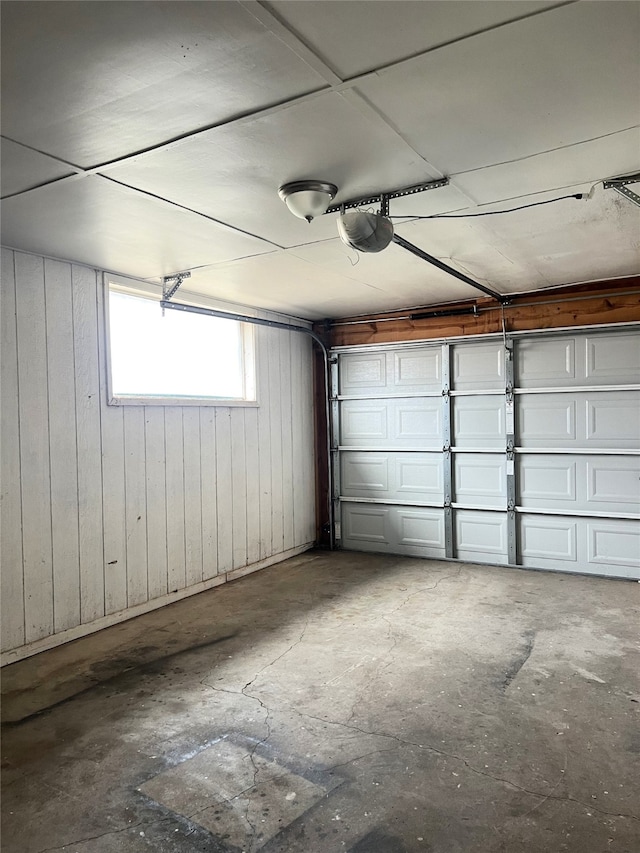 garage with a garage door opener and wood walls