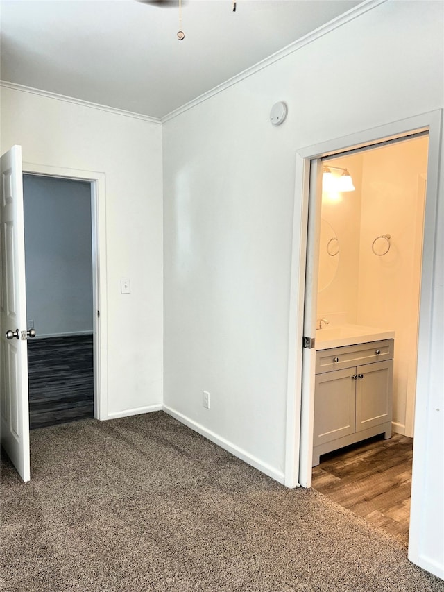 unfurnished bedroom featuring ornamental molding, ensuite bathroom, and carpet floors