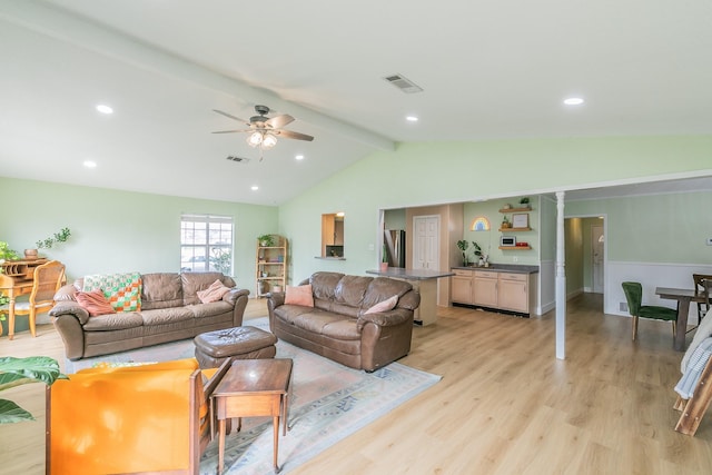 living room with vaulted ceiling with beams, ceiling fan, and light wood-type flooring