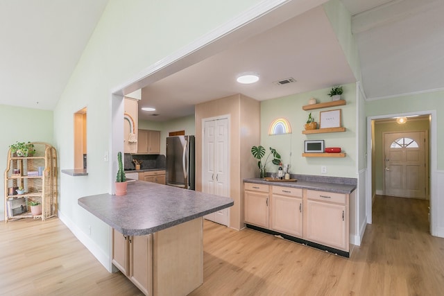 kitchen featuring light wood-type flooring, stainless steel refrigerator, kitchen peninsula, and light brown cabinets