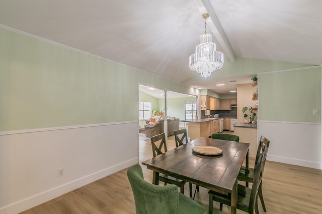 dining area featuring crown molding, vaulted ceiling with beams, a notable chandelier, and light hardwood / wood-style floors