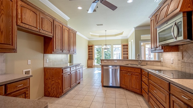 kitchen with sink, light tile patterned floors, appliances with stainless steel finishes, a tray ceiling, and decorative light fixtures