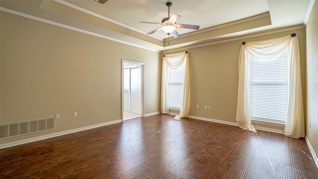 empty room featuring dark hardwood / wood-style floors, ceiling fan, a tray ceiling, and crown molding