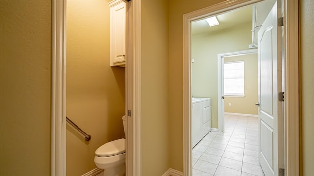 bathroom with tile patterned flooring, washer and dryer, and toilet