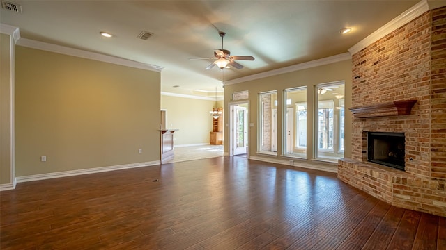 unfurnished living room with crown molding, a fireplace, dark hardwood / wood-style floors, and ceiling fan with notable chandelier