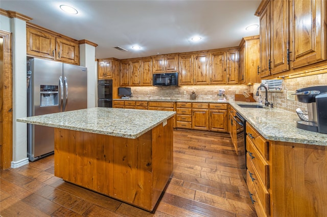 kitchen featuring sink, tasteful backsplash, a center island, dark hardwood / wood-style flooring, and black appliances