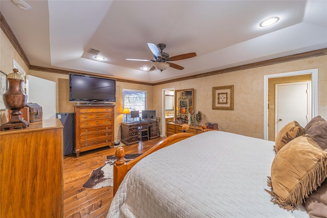 bedroom featuring a raised ceiling, crown molding, hardwood / wood-style flooring, and ceiling fan