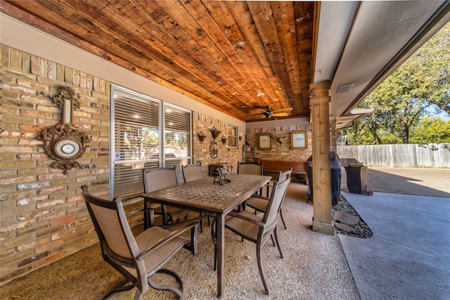 dining space with wood ceiling, ceiling fan, and brick wall