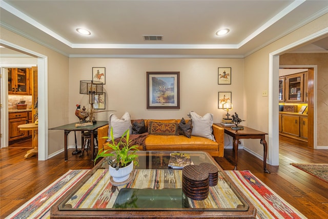 living room featuring crown molding, dark hardwood / wood-style floors, and a raised ceiling