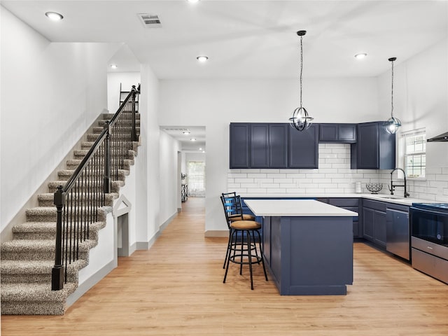 kitchen with sink, a breakfast bar, stainless steel appliances, a center island, and light hardwood / wood-style floors