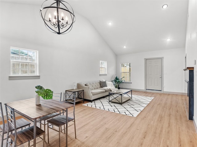 living room with high vaulted ceiling, a chandelier, light hardwood / wood-style floors, and a wealth of natural light