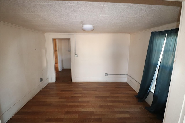 spare room with ornamental molding and dark hardwood / wood-style flooring