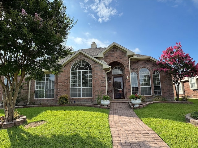 2414 W Stillwater Dr, Mesquite, TX 75181 - view of front of home with a front yard, a chimney, and brick siding