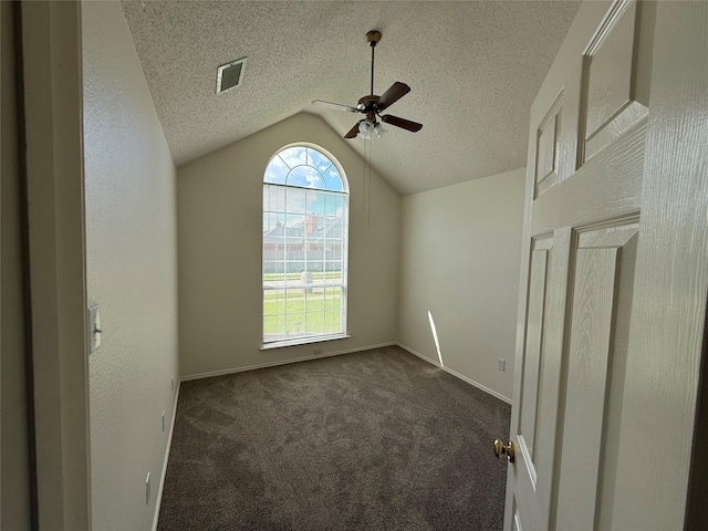 2414 W Stillwater Dr, Mesquite, TX 75181 - empty room featuring a ceiling fan, lofted ceiling, dark carpet, and a textured ceiling