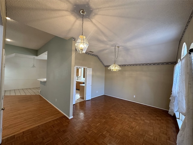 spare room featuring lofted ceiling, a textured ceiling, and dark parquet floors