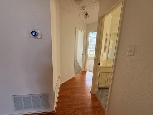 2414 W Stillwater Dr, Mesquite, TX 75181 - hallway with a textured wall, wood finished floors, and a textured ceiling