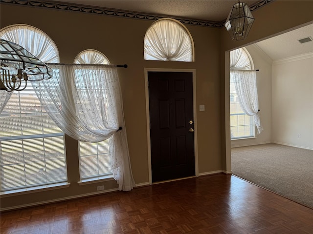 entryway featuring crown molding, dark parquet flooring, and a textured ceiling