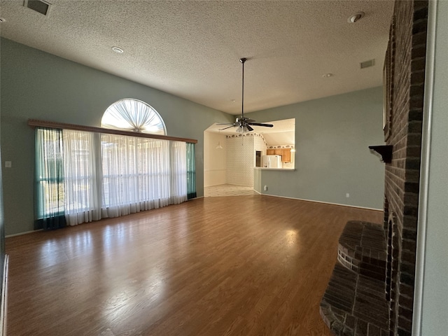 unfurnished living room with ceiling fan, hardwood / wood-style floors, a textured ceiling, and a fireplace