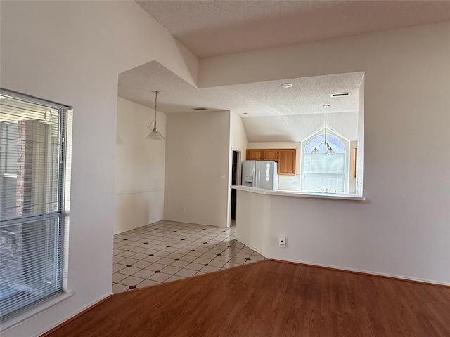 2414 W Stillwater Dr, Mesquite, TX 75181 - unfurnished dining area featuring a textured ceiling, light wood-style floors, and vaulted ceiling
