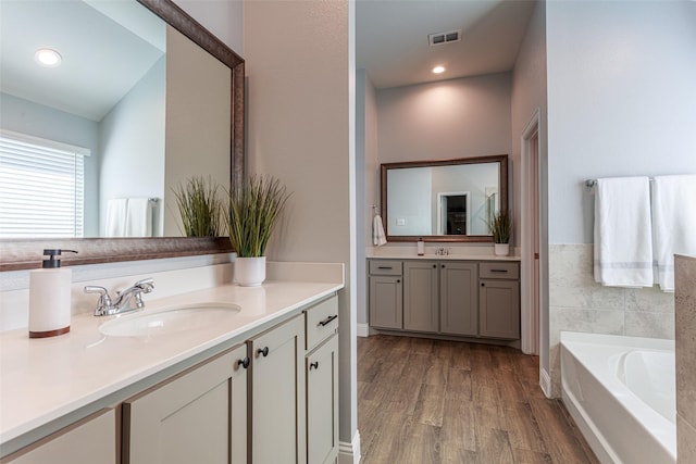 bathroom with wood-type flooring, a bathing tub, and vanity