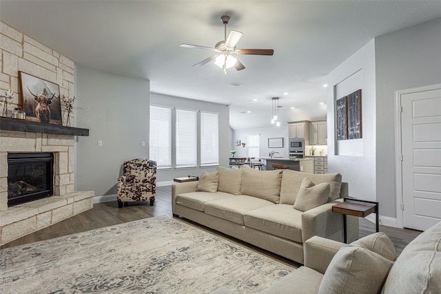 living room featuring dark wood-type flooring, ceiling fan, and a fireplace