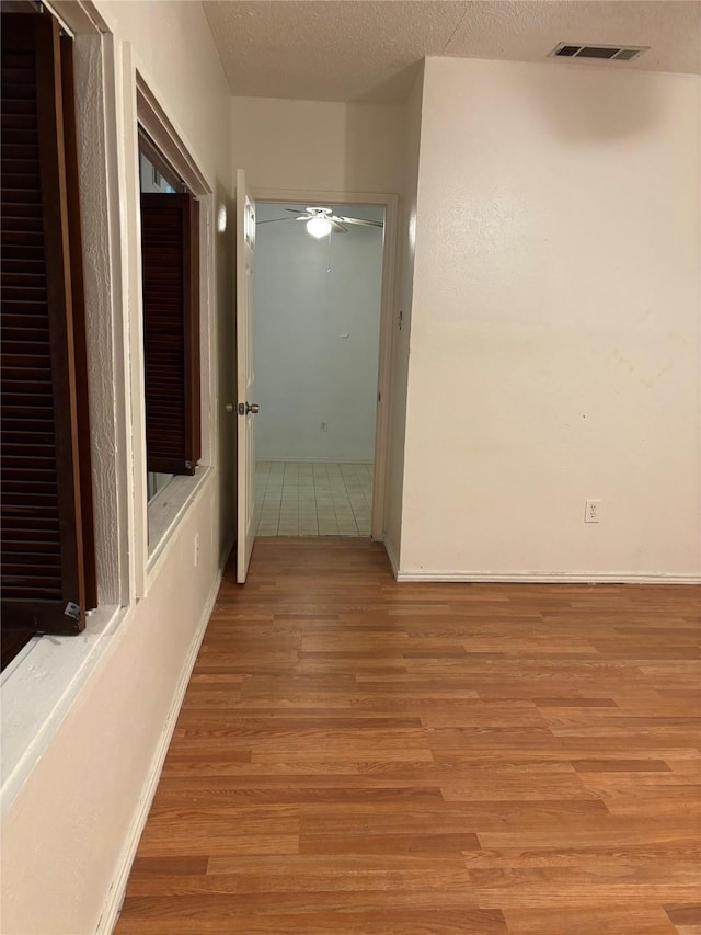 hall with light hardwood / wood-style flooring and a textured ceiling