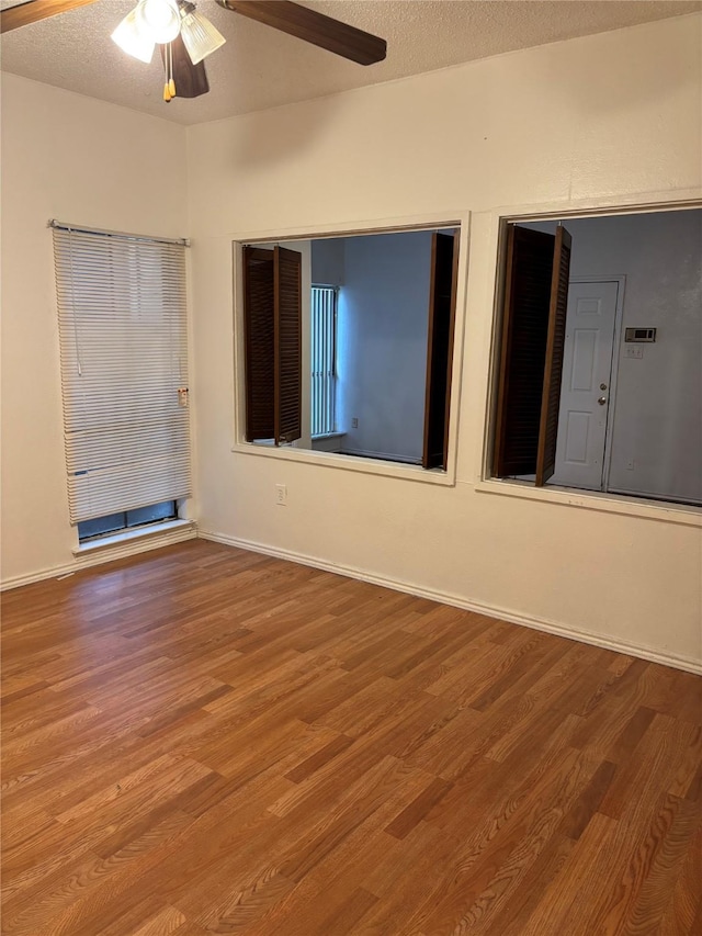 empty room with ceiling fan, hardwood / wood-style flooring, and a textured ceiling