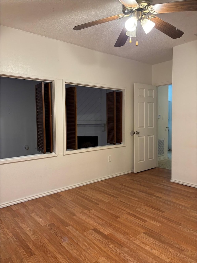 unfurnished room featuring ceiling fan, light hardwood / wood-style flooring, and a textured ceiling