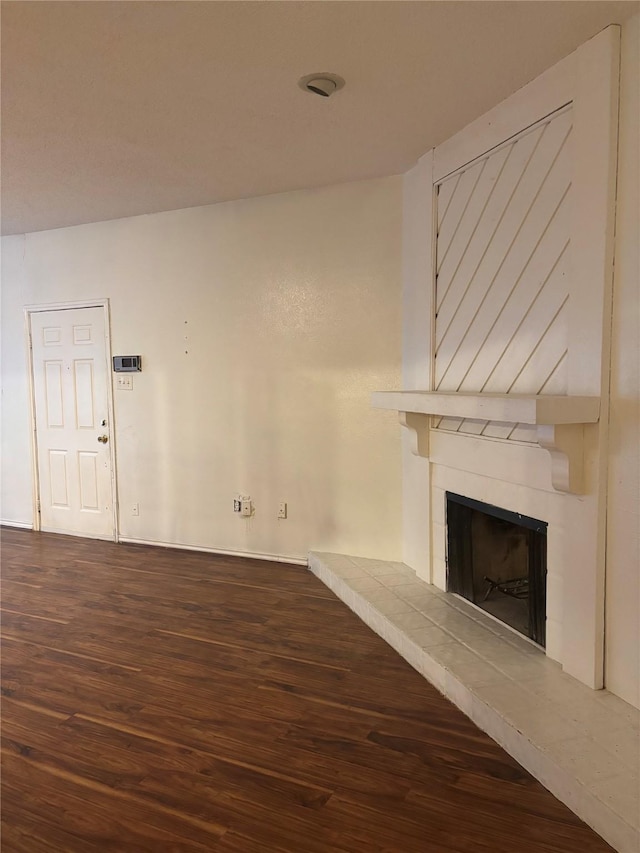 unfurnished living room with hardwood / wood-style flooring and a tile fireplace