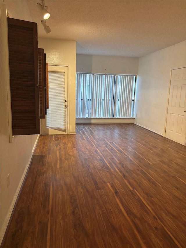 spare room with a textured ceiling and dark hardwood / wood-style flooring