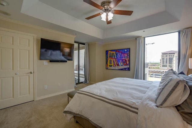 bedroom with ceiling fan, access to exterior, a tray ceiling, ornamental molding, and light carpet