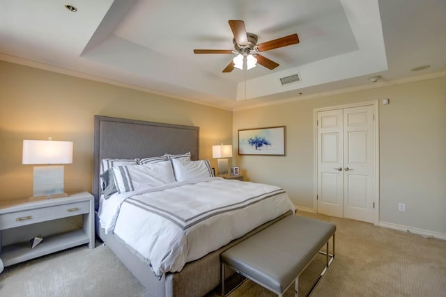 bedroom featuring a raised ceiling, crown molding, light carpet, and a closet